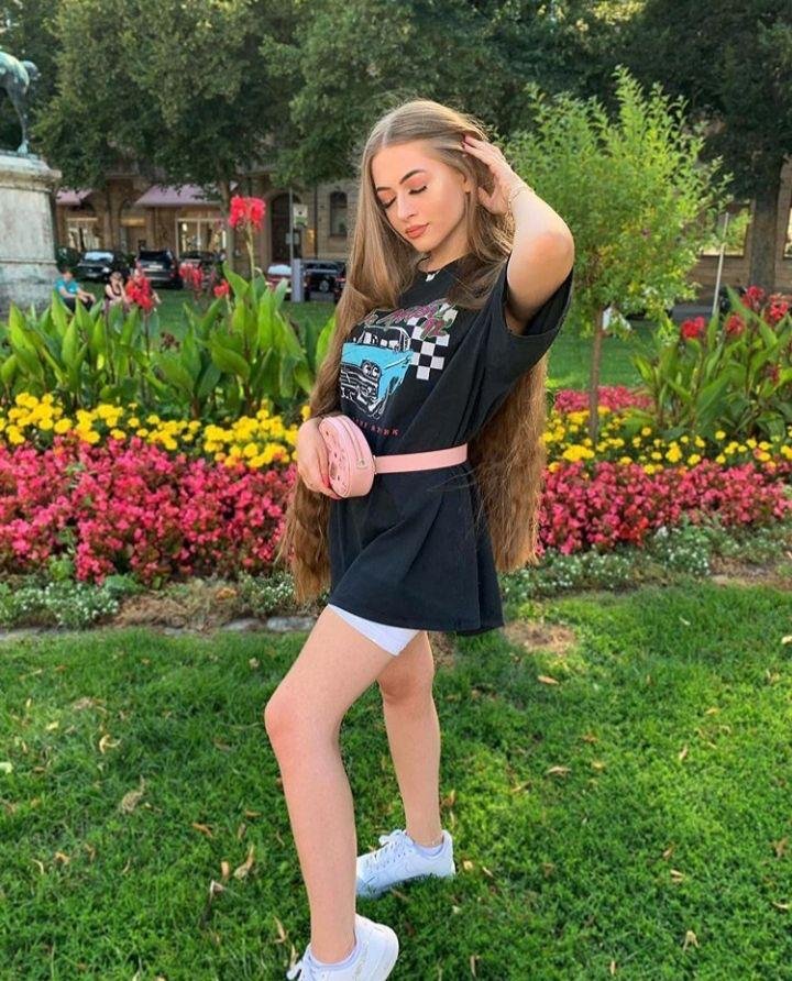 Chica de pie entre flores con camiseta negra