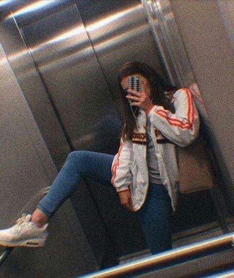 Selfie en el espejo de un ascensor tapándose la cara