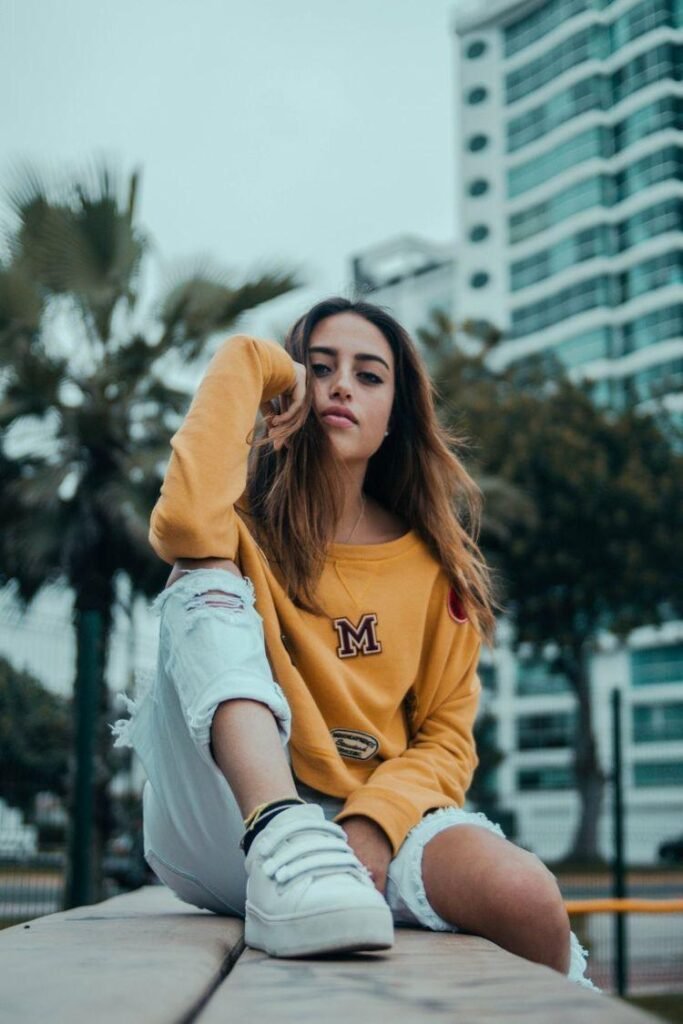 Chica sentada en un muro con palmeras de fondo