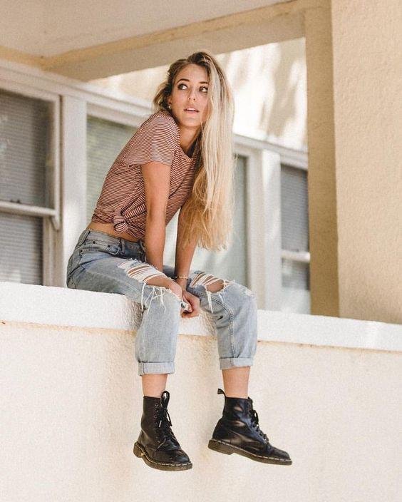 Chica sentada en un muro con botas negras
