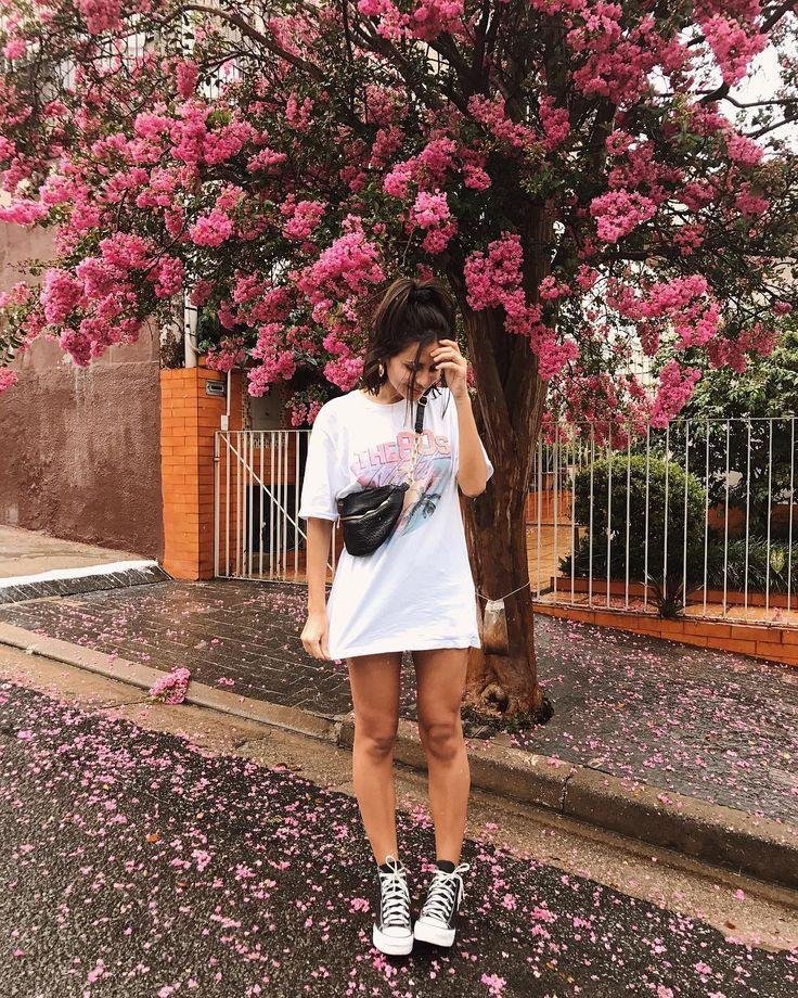 Chica de pie bajo un árbol con flores rosas