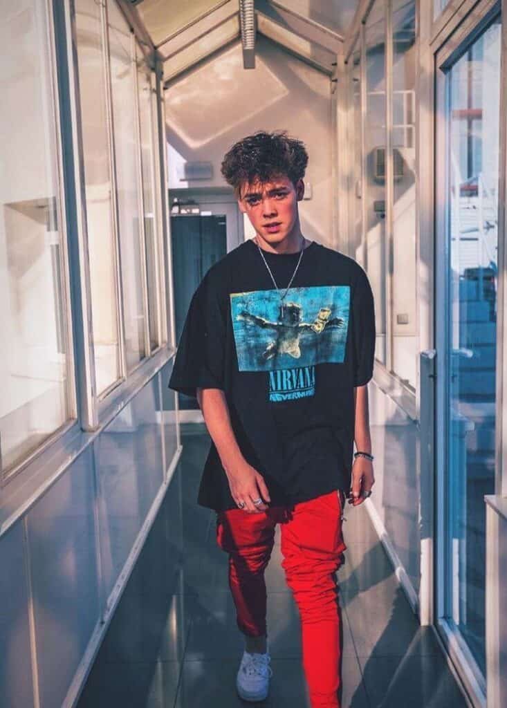 Chico de cuerpo entero en un pasillo con camiseta estampada