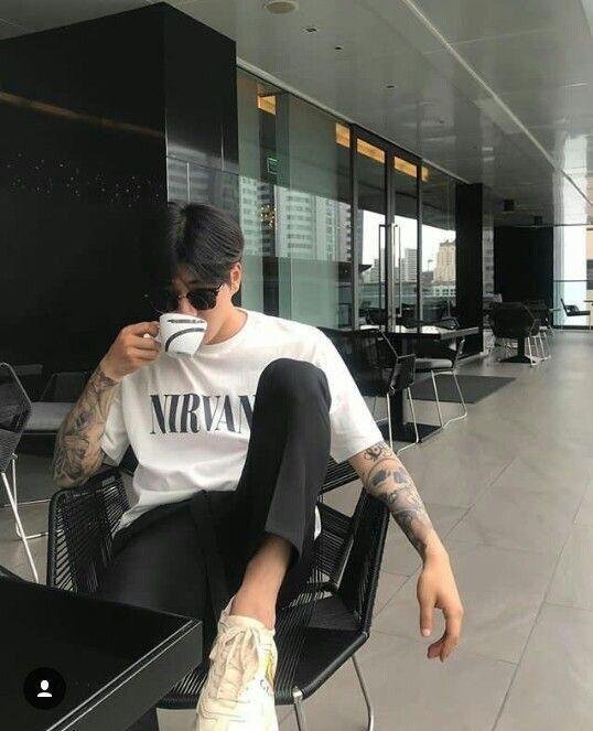 Chico sentado en una silla con las piernas cruzadas y tatuajes