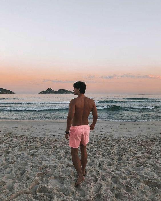 Chico de espaldas caminando por la playa al atardecer