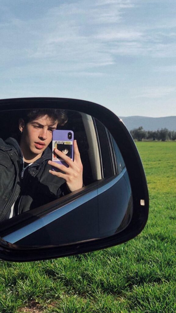 Selfie en el retrovisor del coche con el campo de fondo