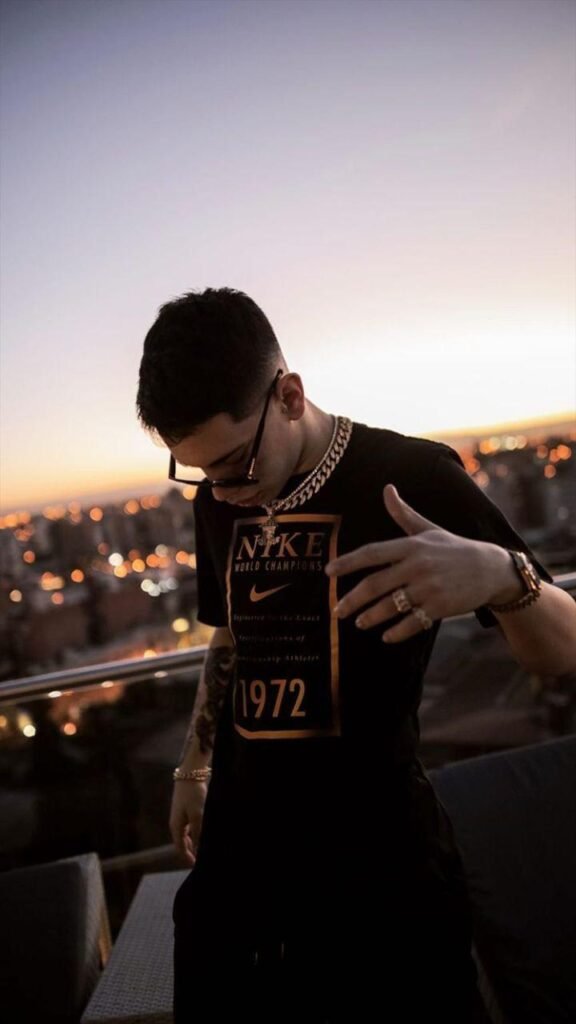 Chico apoyado en una barandilla al atardecer con la ciudad de fondo