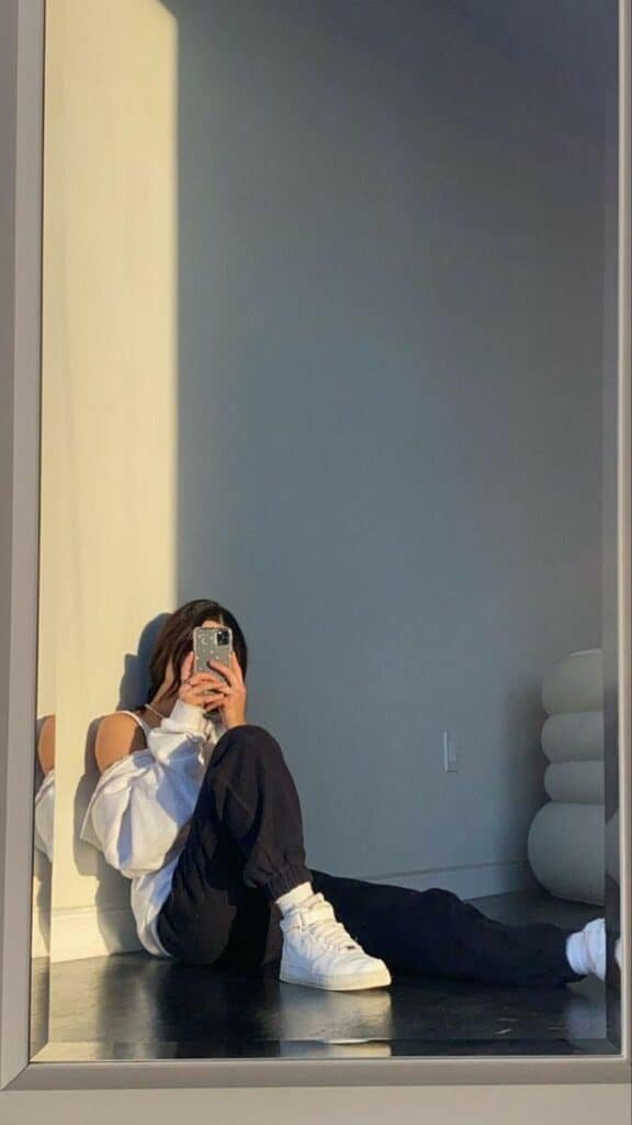 Chica sentada en el suelo con las piernas estiradas hacia el espejo