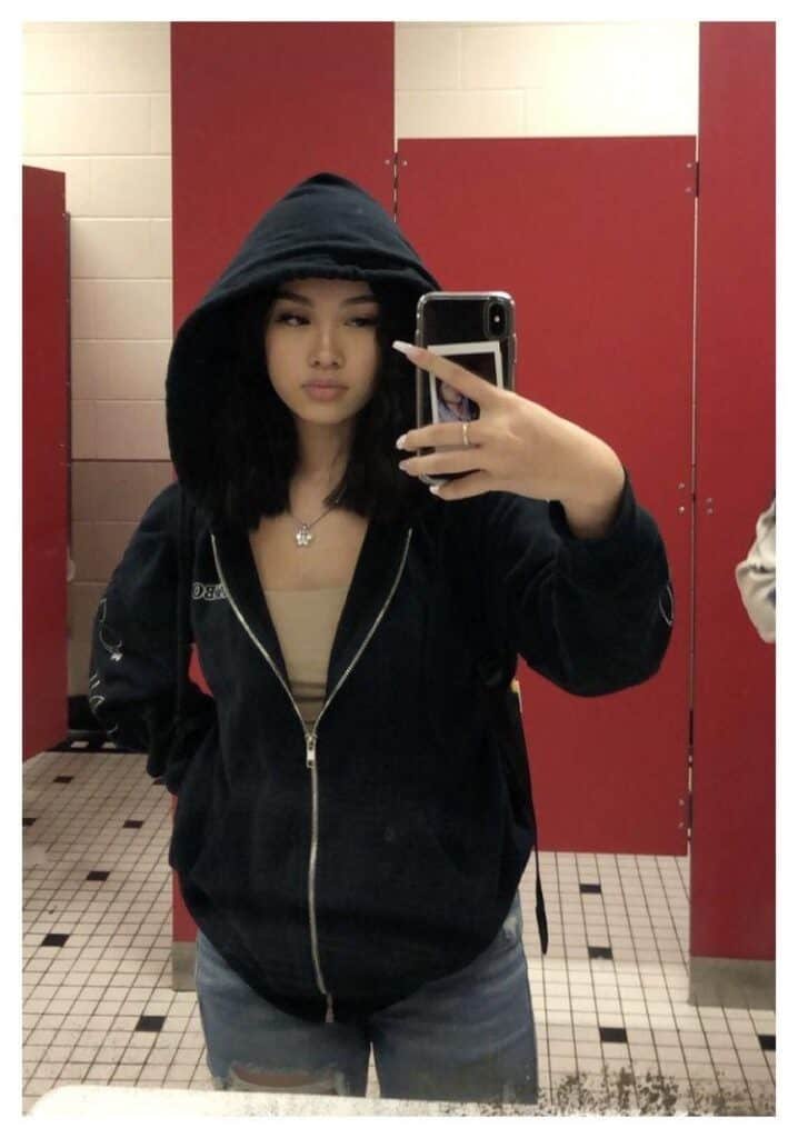 Cuerpo entero con sudadera con capucha en un baño de azulejos