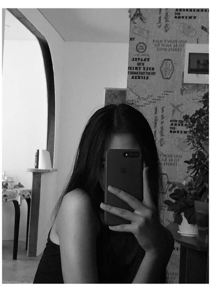 Foto en blanco y negro de cuerpo entero con el móvil tapando la cara