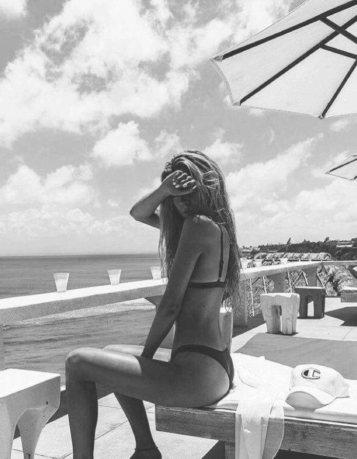 Foto en blanco y negro sentada de espaldas junto a la piscina