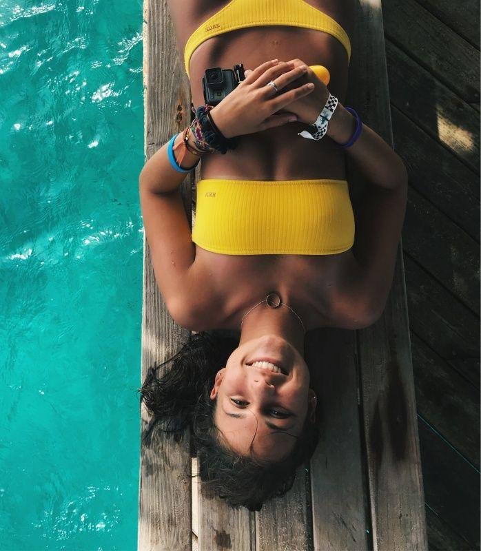 Chica tumbada boca arriba en el borde de la piscina
