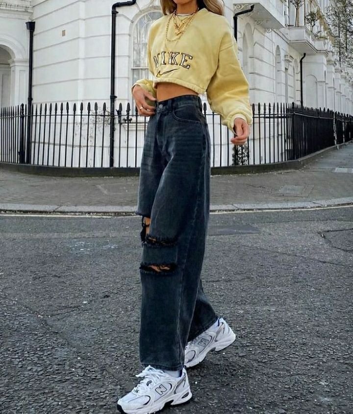 Sudadera amarilla con jeans anchos oscuros rotos