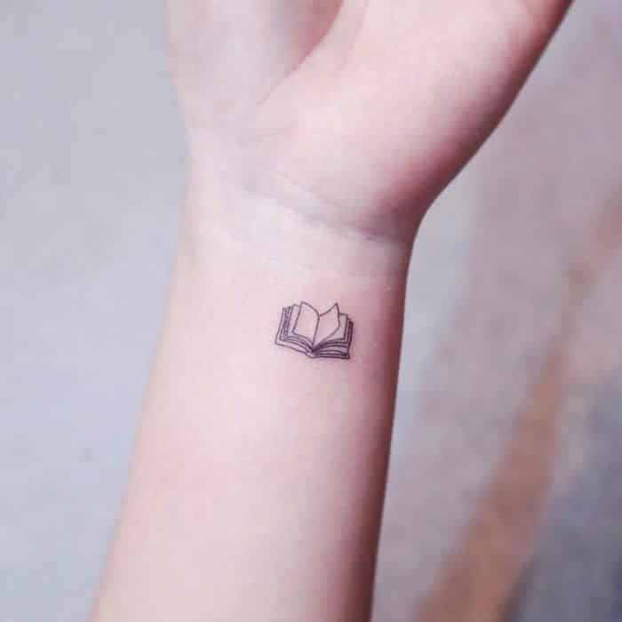 Libro abierto diminuto tatuado en la muñeca
