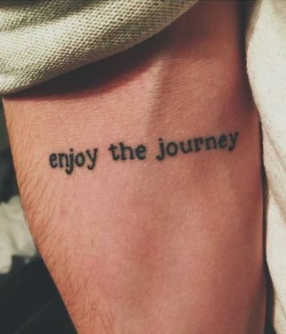 Frase 'enjoy the journey' tatuada en el brazo