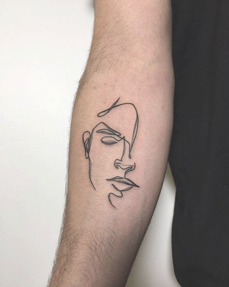 Cara dibujada de una sola línea tatuada en el antebrazo