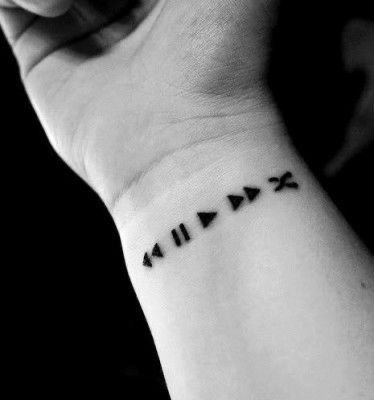 Símbolos de reproducción tatuados en fila en la muñeca