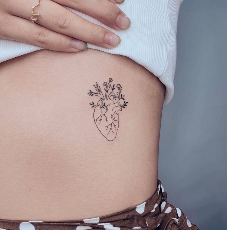 Corazón anatómico con flores tatuado en la cadera
