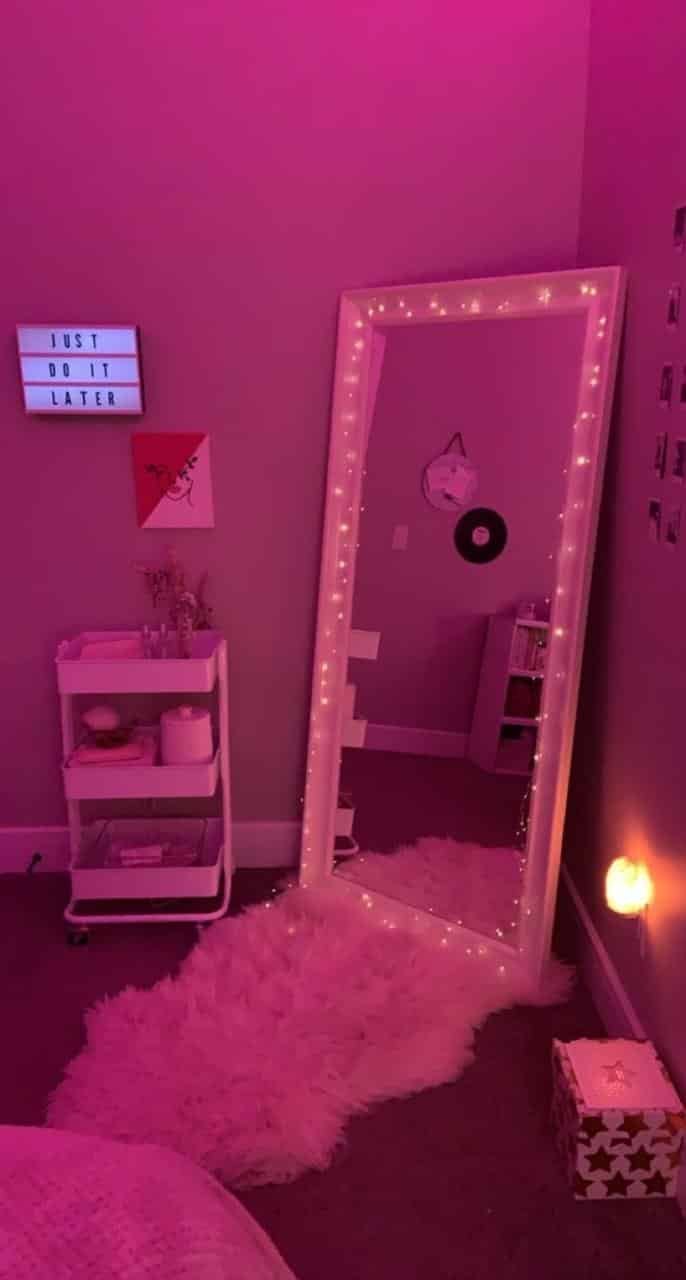 Espejo de cuerpo entero rodeado de luces en un cuarto rosa