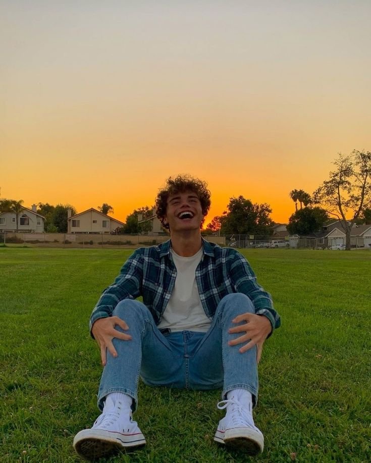 Chico sentado en el césped al atardecer