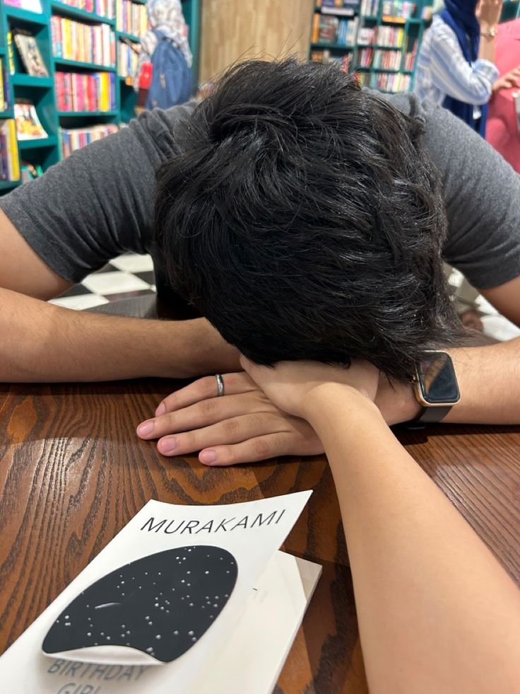 Pareja apoyada en una mesa de librería con un libro