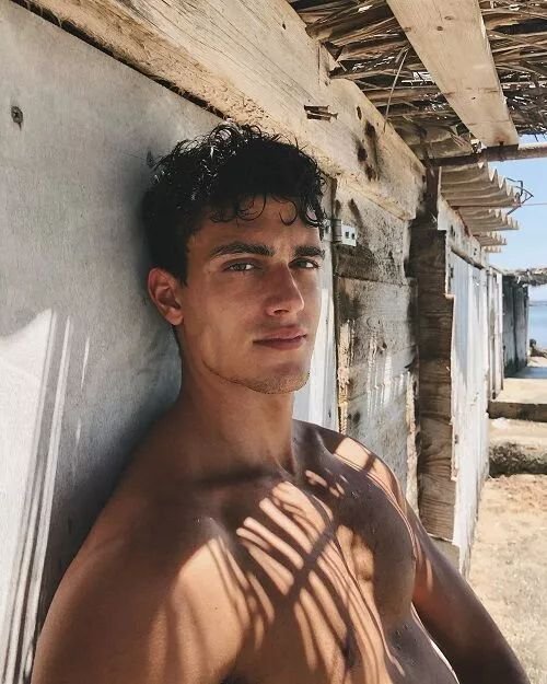 Chico apoyado en una pared con sombras de la luz del sol