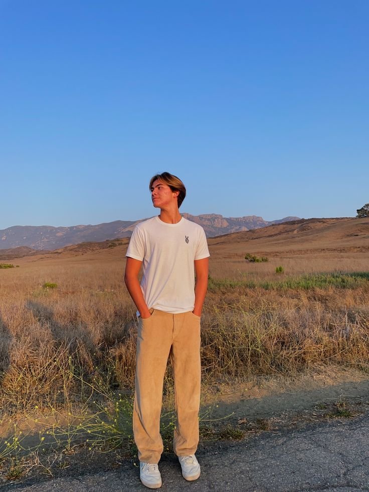 Chico de pie en el campo con camiseta blanca
