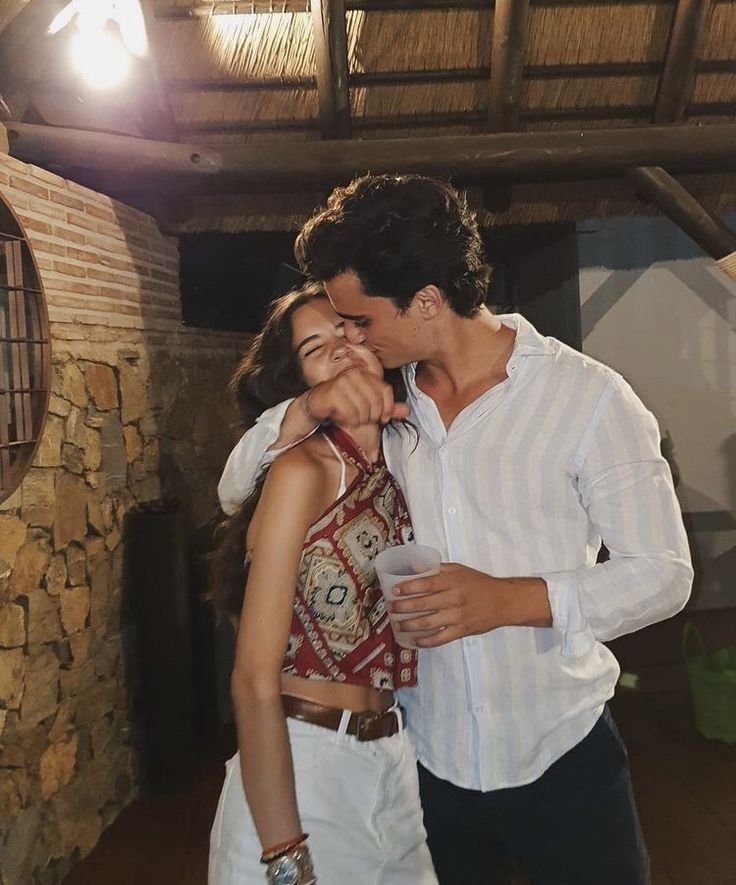 Pareja de pie mientras él la besa en la mejilla