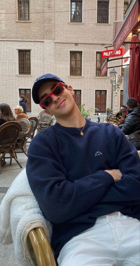 Chico sentado en una terraza con gorra y gafas de sol