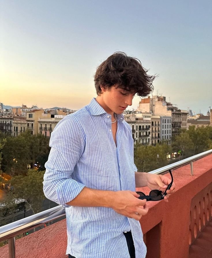 Chico apoyado en una barandilla al atardecer