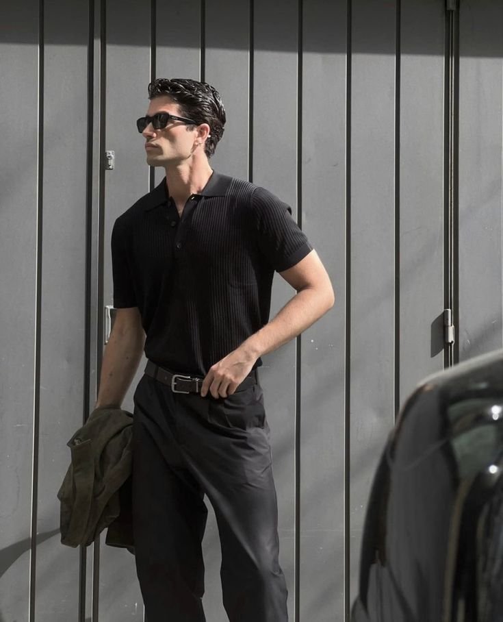 Chico de pie contra una verja con polo negro