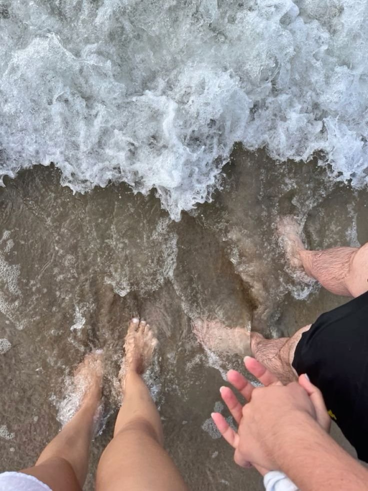 Pies de una pareja en la orilla del mar vistos desde arriba