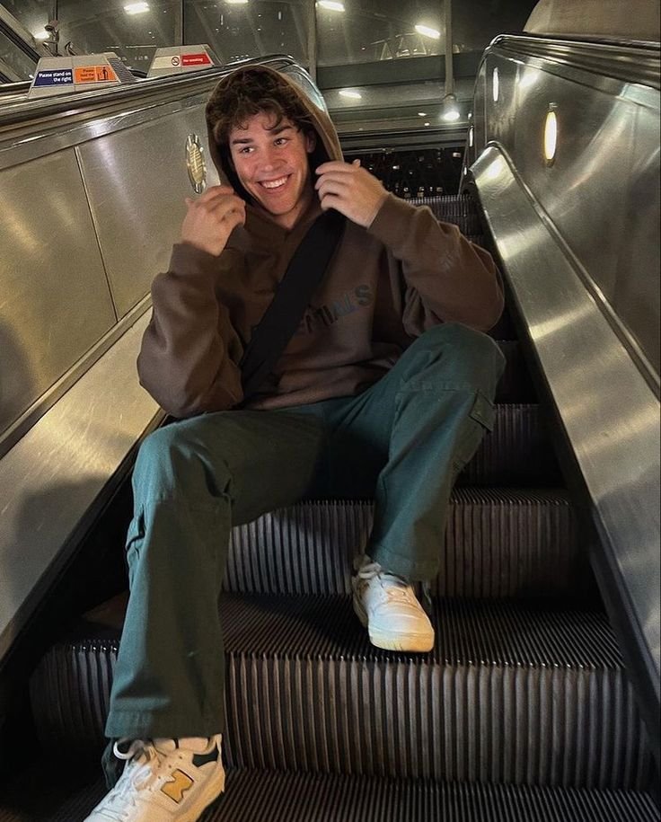 Chico sentado en unas escaleras mecánicas