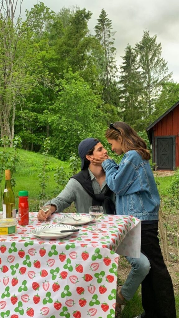 Pareja desayunando en el campo con mantel de fresas