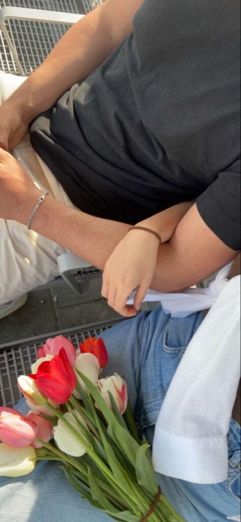 Detalle de las manos de una pareja sobre unos tulipanes