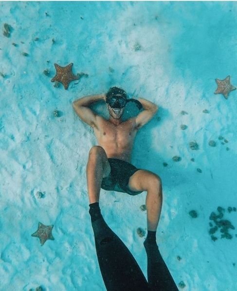 Chico flotando de espaldas en agua turquesa, visto desde arriba