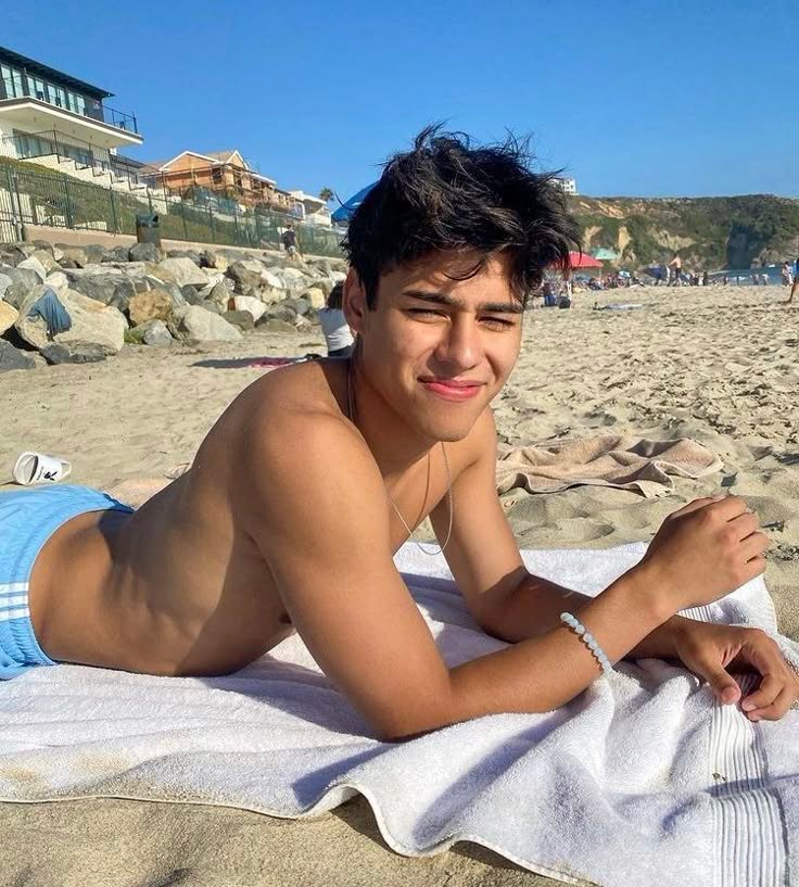 Chico tumbado sobre una toalla en la arena