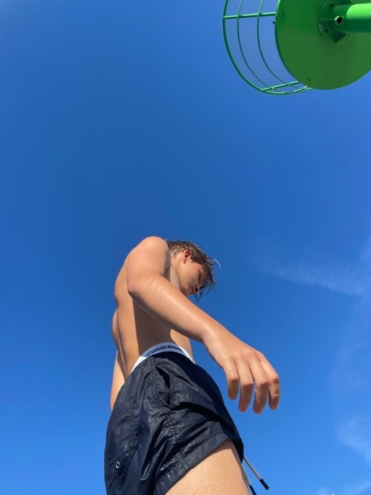 Foto en contrapicado de un chico con el cielo azul de fondo