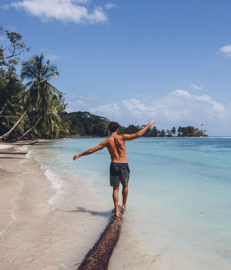 Chico caminando sobre un tronco en la playa