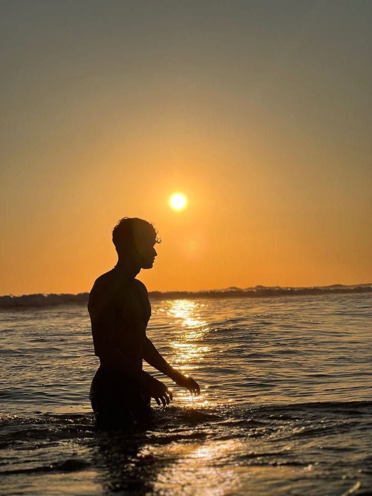 Chico de pie en el agua recortado contra el sol