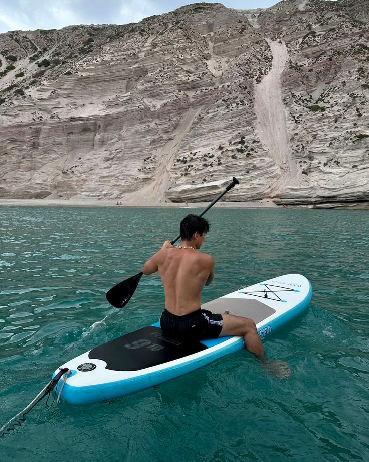 Chico sentado sobre una tabla de paddle surf