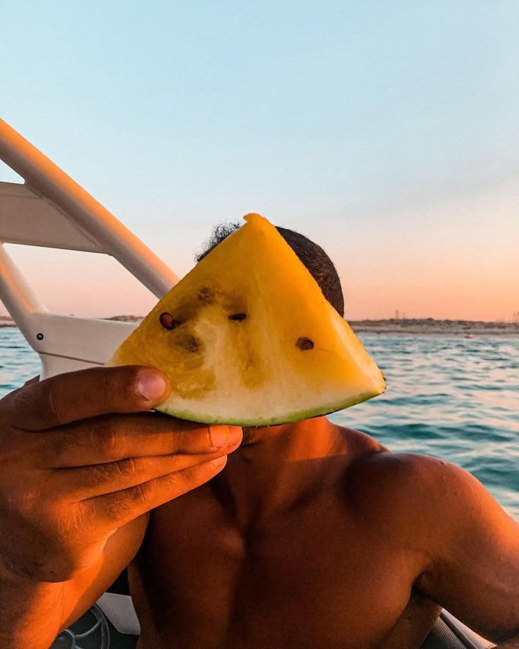 Chico comiendo sandía en un barco al atardecer