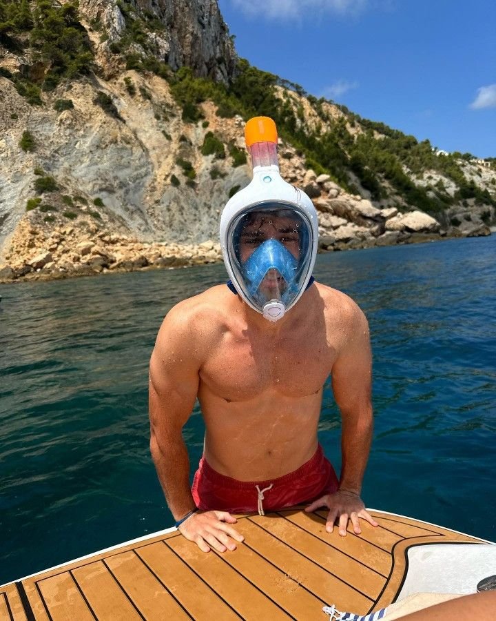 Chico con máscara de snorkel sentado en la popa de un barco