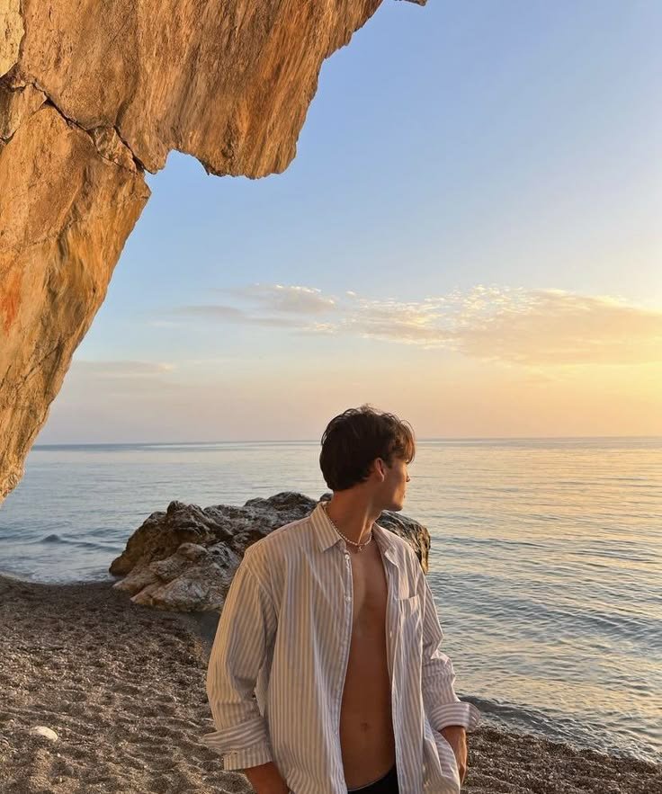 Chico apoyado en una roca junto al mar al atardecer