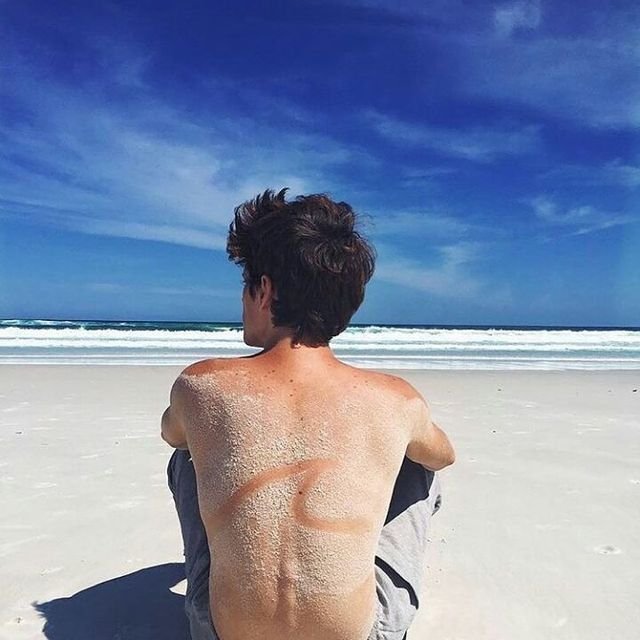 Chico de espaldas sentado frente al mar
