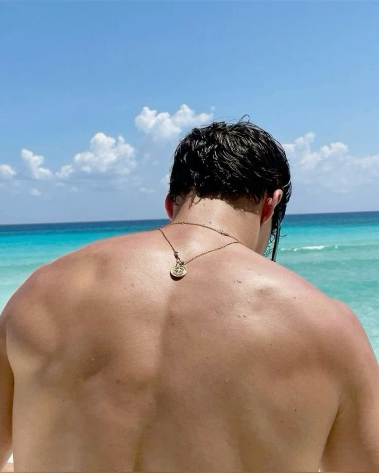 Chico de espaldas con el mar turquesa de fondo