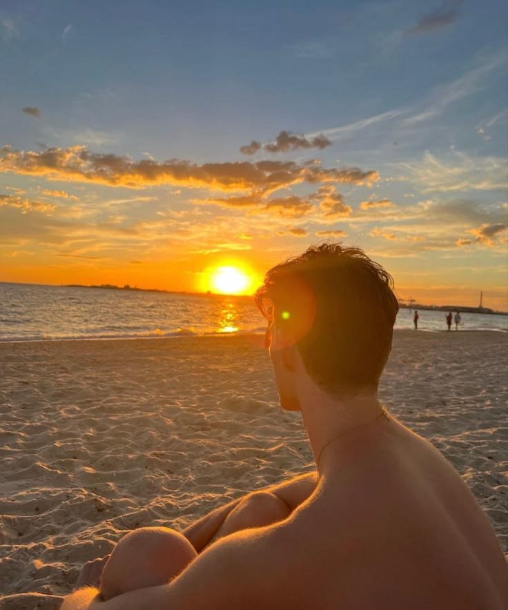 Chico de espaldas frente al sol poniéndose en el mar