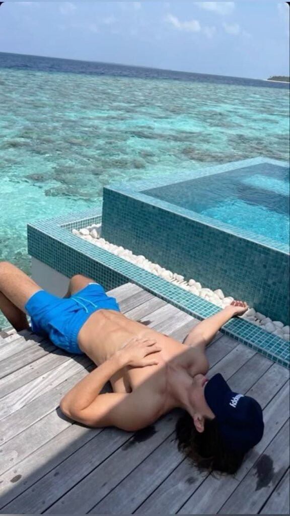 Chico tumbado junto a una piscina infinita frente al mar