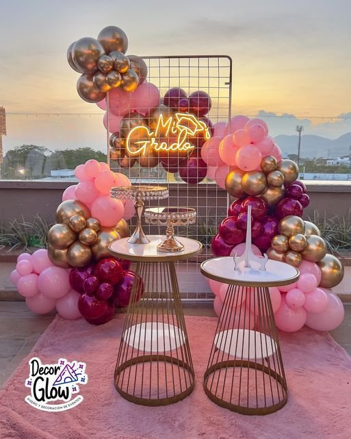 Montaje de globos rosas y burdeos con mesas altas doradas