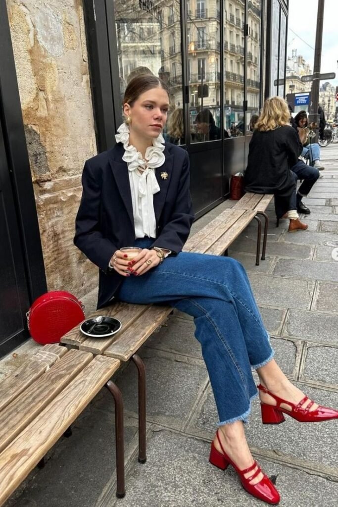 Blazer azul marino con camisa de volantes y zapatos rojos