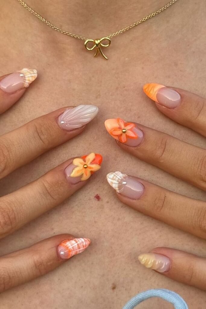 Uñas nude con flores naranjas pintadas